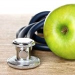 Photo of an apple on a table with a stethoscope next to it