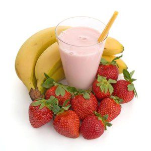 pink smoothie in a glass surrounded by fresh strawberries and bananas