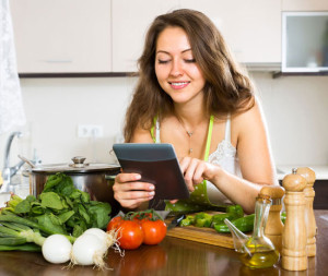 Cherubino-Health-Center-Blog-Photo Woman standing at a countertop with raw vegetables reading Cherubino Health Center blogs about health and nutrition
