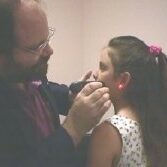 Photo of Dr Cherubino treating a child with red laser light therapy