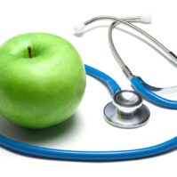 Stethoscope with green apple on white