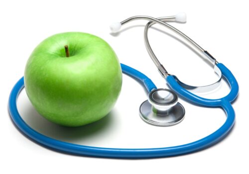 Stethoscope with green apple on white