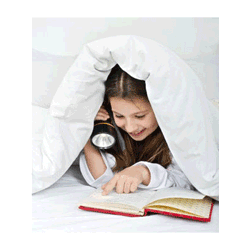 Young girl reading a book by flashlight under the covers