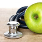 Photo of a stethoscope and an apple on a table