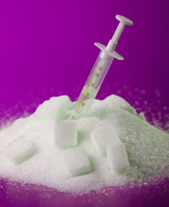 Hypodermic needle stuck into amount of white sugar with brilliant purple background reversing diabetes article