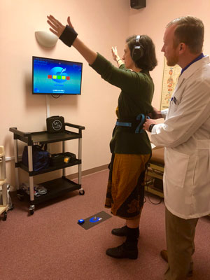 Dr Lars Landers helping a patient perform Interactive Metronome at Cherubino Health Center