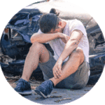 Photo of a man sitting on the ground head on his arm after traumatic brain injury from motor vehicle accident