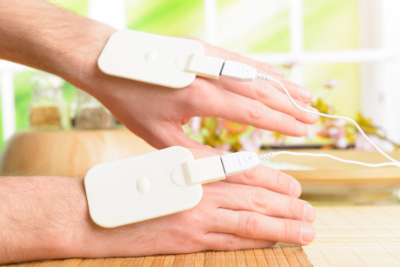 Photo of a patient's hands with low current electrical therapy pads